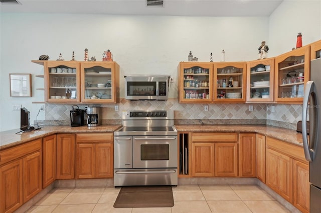 kitchen featuring light tile patterned floors, stainless steel appliances, and light stone counters