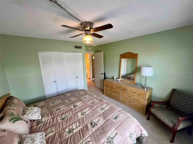 bedroom featuring a textured ceiling, light colored carpet, a closet, and ceiling fan