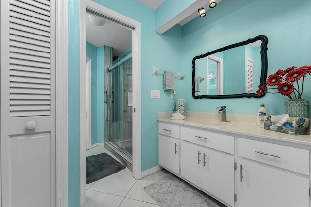 bathroom featuring vanity, a shower with shower door, a textured ceiling, and tile patterned floors