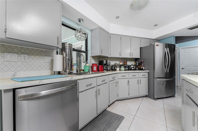 kitchen featuring gray cabinetry, sink, stainless steel appliances, decorative backsplash, and light tile patterned floors