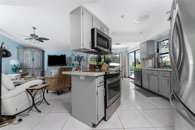 kitchen featuring kitchen peninsula, ceiling fan, light tile patterned flooring, gray cabinets, and stainless steel appliances