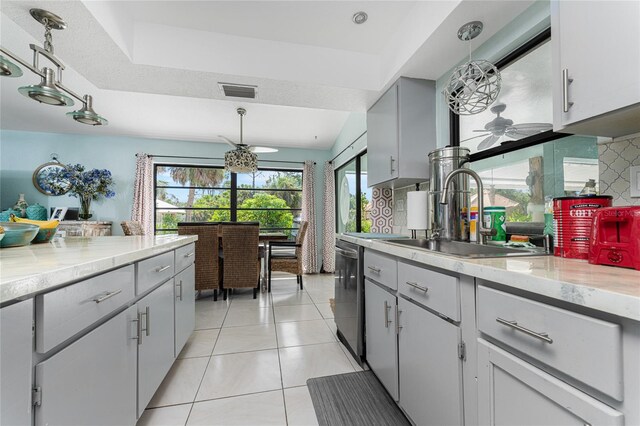 kitchen featuring dishwasher, gray cabinetry, sink, light tile patterned flooring, and decorative light fixtures