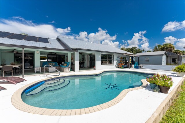 view of swimming pool with a patio, a storage shed, and ceiling fan