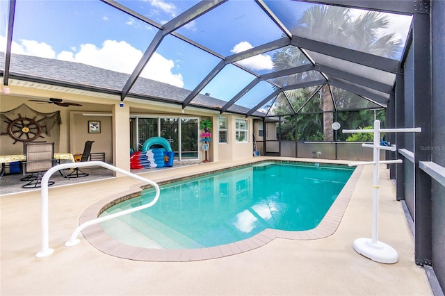 view of pool with glass enclosure, ceiling fan, and a patio