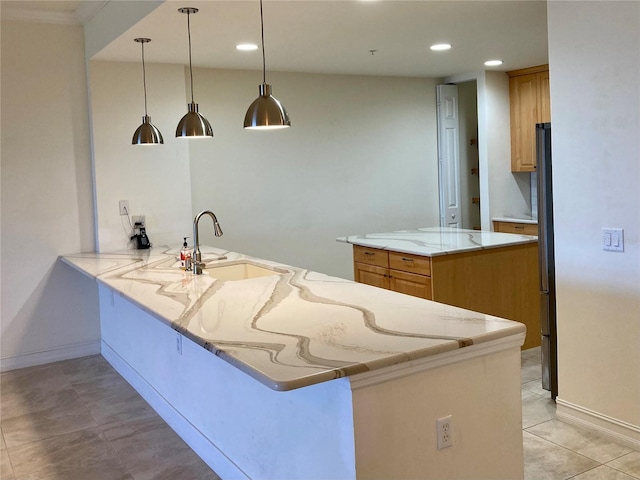 kitchen featuring kitchen peninsula, sink, light stone countertops, fridge, and decorative light fixtures