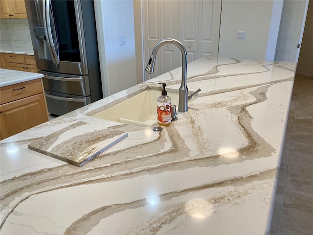 room details with decorative backsplash, light brown cabinets, sink, and stainless steel fridge with ice dispenser