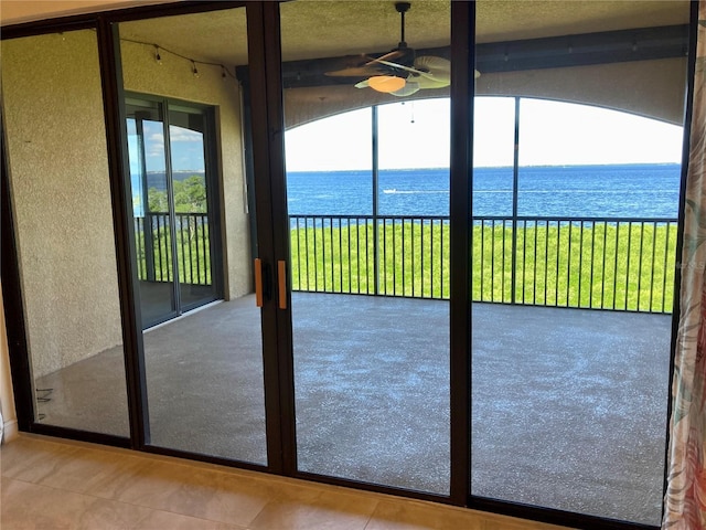 entryway featuring a water view, ceiling fan, and tile patterned floors