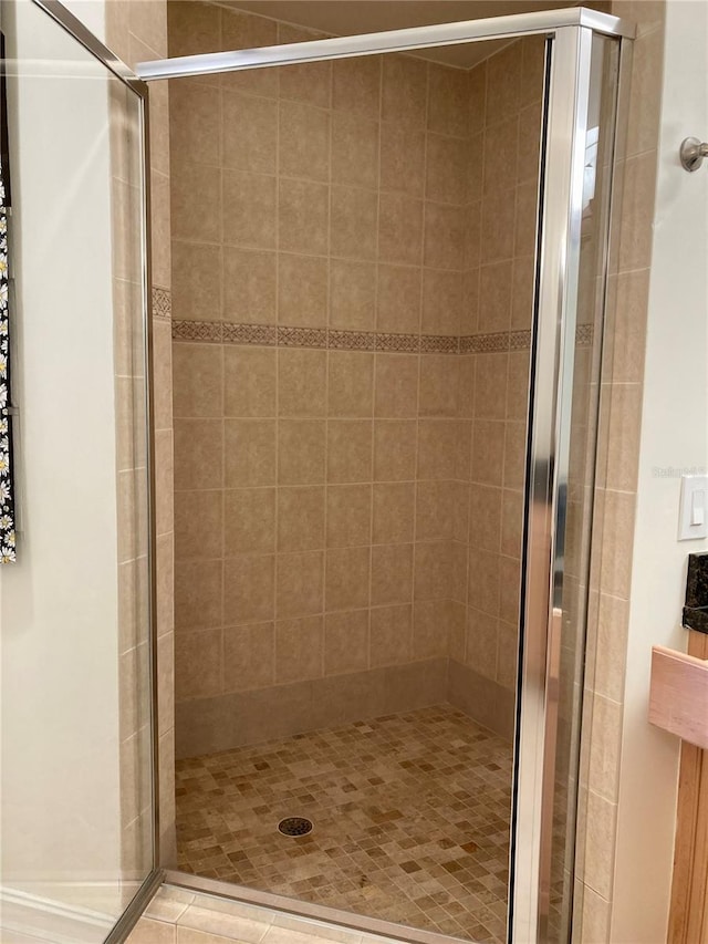 bathroom with an enclosed shower and tile patterned flooring