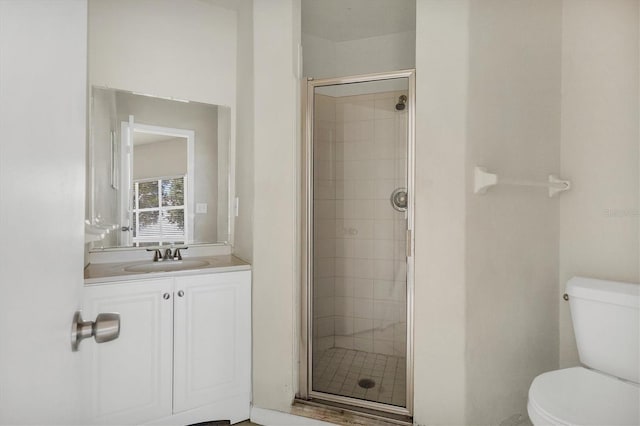 bathroom featuring vanity, toilet, and a shower with door