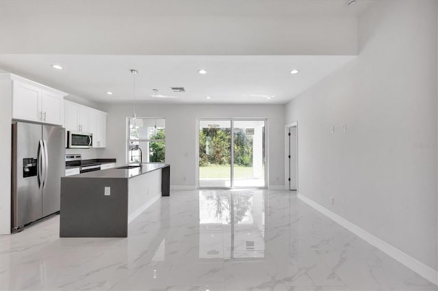 kitchen featuring stainless steel appliances, a center island with sink, sink, decorative light fixtures, and white cabinets