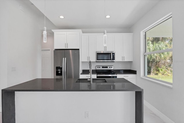 kitchen with sink, white cabinets, decorative light fixtures, and stainless steel appliances