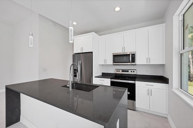 kitchen with sink, white cabinetry, stainless steel appliances, decorative light fixtures, and a center island with sink