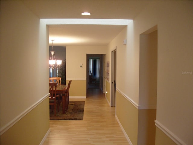 hallway featuring wood-type flooring and a chandelier