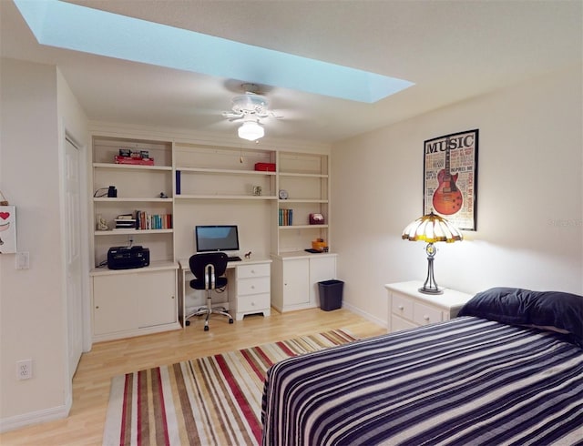 bedroom featuring ceiling fan, a skylight, and light hardwood / wood-style flooring