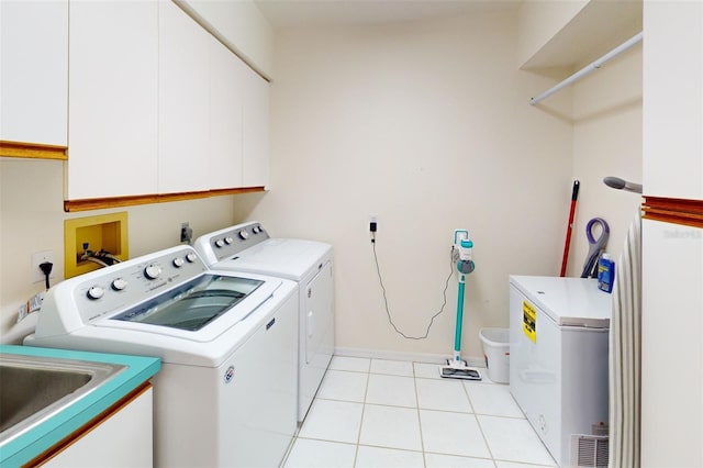 washroom with light tile patterned floors, washing machine and dryer, and cabinets