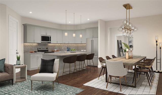 kitchen featuring tasteful backsplash, dark hardwood / wood-style flooring, appliances with stainless steel finishes, a kitchen island with sink, and light stone counters