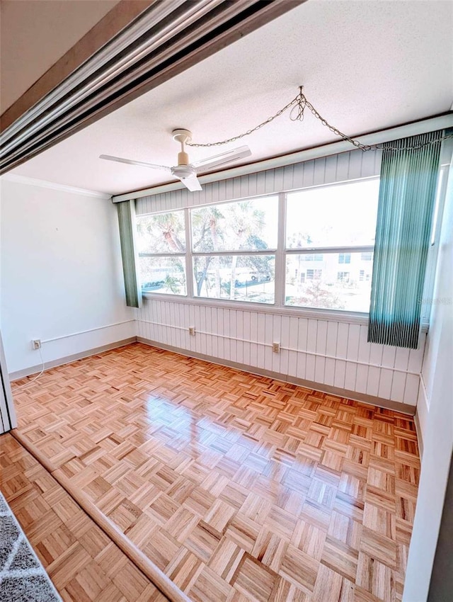 empty room featuring a textured ceiling, light parquet floors, and ceiling fan