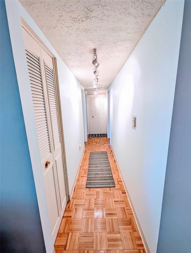 corridor featuring a textured ceiling and light parquet flooring