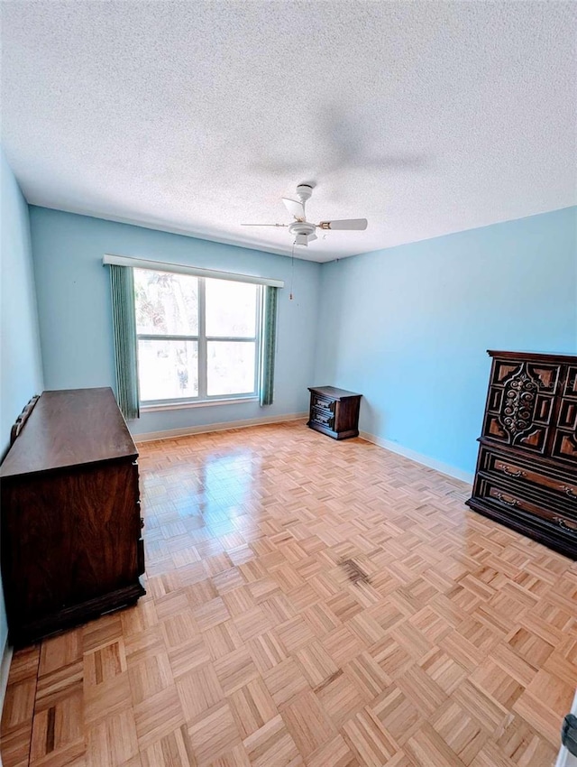 interior space featuring a textured ceiling, light parquet flooring, and ceiling fan