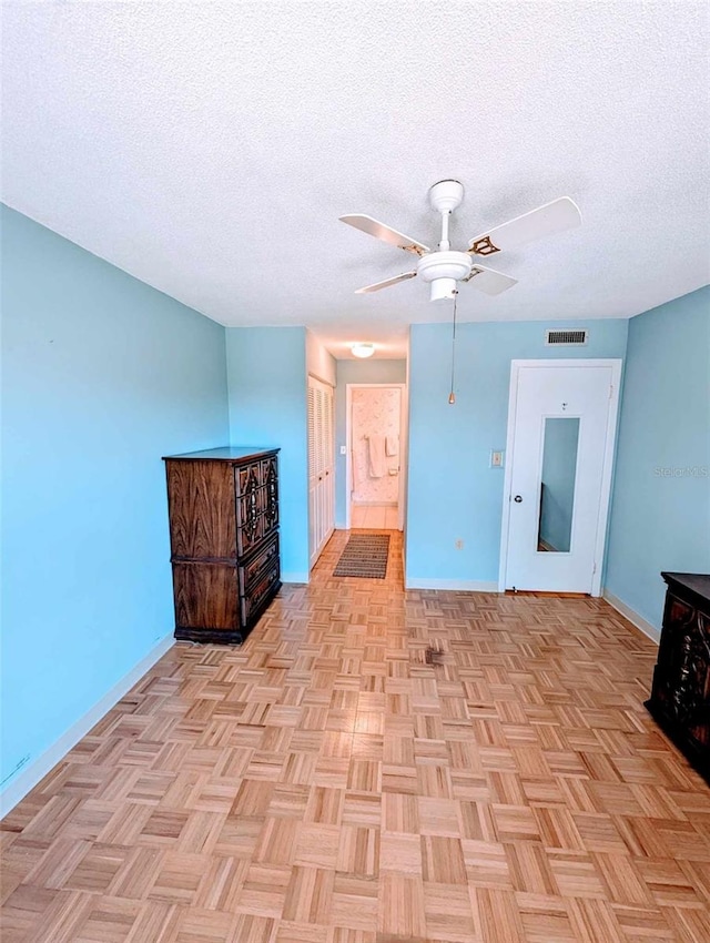 unfurnished room featuring ceiling fan, light parquet flooring, and a textured ceiling