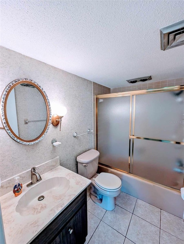 full bathroom featuring bath / shower combo with glass door, a textured ceiling, toilet, vanity, and tile patterned floors