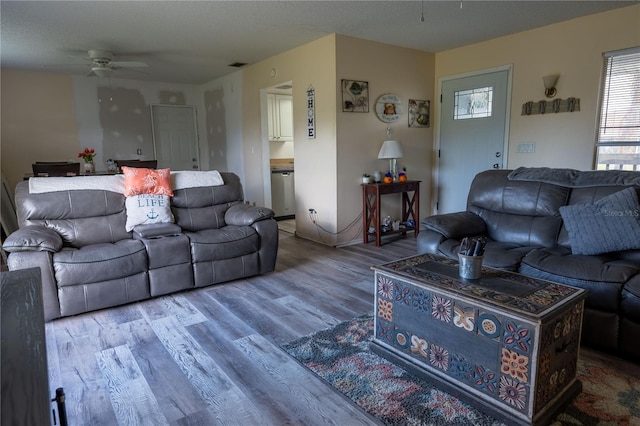 living room with ceiling fan, a textured ceiling, and hardwood / wood-style floors