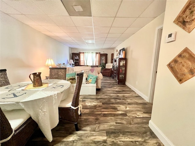 dining space with a drop ceiling and dark hardwood / wood-style flooring