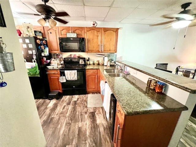 kitchen featuring black appliances, sink, dark hardwood / wood-style flooring, kitchen peninsula, and a paneled ceiling