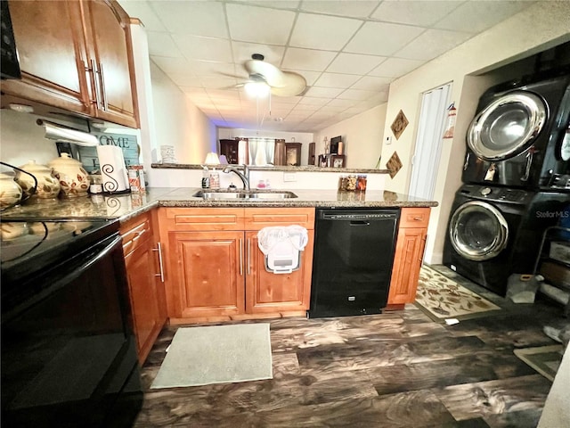 kitchen with kitchen peninsula, ceiling fan, stacked washing maching and dryer, black appliances, and sink