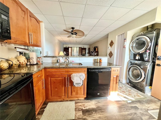 kitchen featuring black appliances, sink, kitchen peninsula, light hardwood / wood-style floors, and stacked washer and dryer