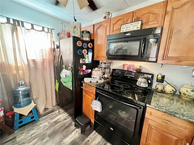 kitchen featuring light hardwood / wood-style floors, light stone countertops, black appliances, and ceiling fan