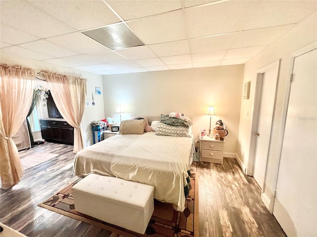 bedroom with wood-type flooring and a drop ceiling