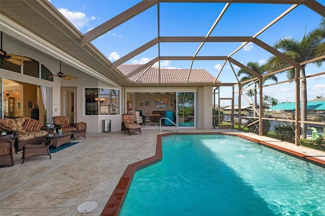 view of pool with a patio, glass enclosure, a water view, and ceiling fan