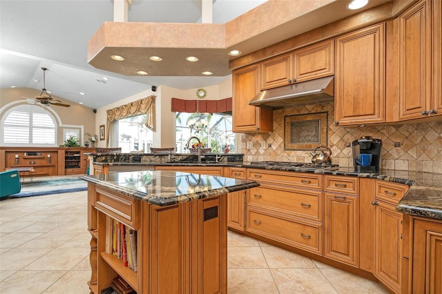 kitchen featuring lofted ceiling, ceiling fan, sink, stainless steel gas cooktop, and a center island