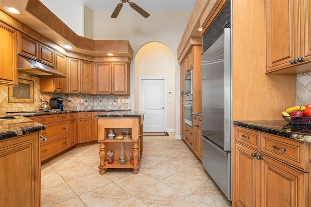 kitchen with decorative backsplash, stainless steel appliances, a center island, light tile patterned floors, and ceiling fan