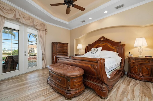 bedroom with ceiling fan, access to exterior, a tray ceiling, light hardwood / wood-style flooring, and crown molding