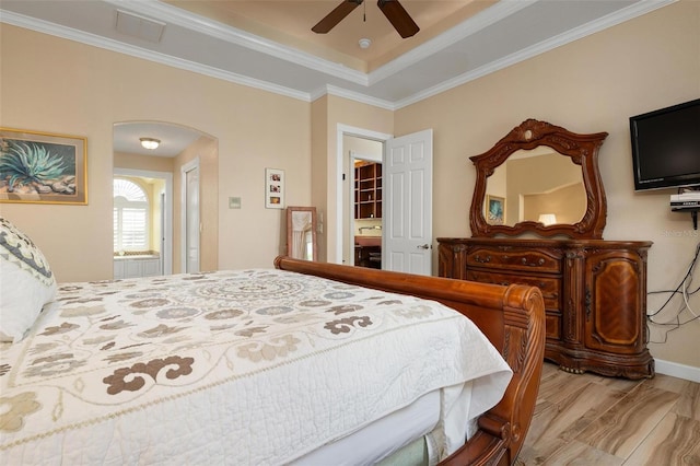 bedroom featuring crown molding, a raised ceiling, light hardwood / wood-style floors, and ceiling fan