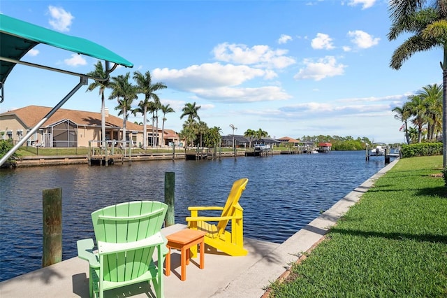 view of dock featuring a water view, glass enclosure, and a lawn