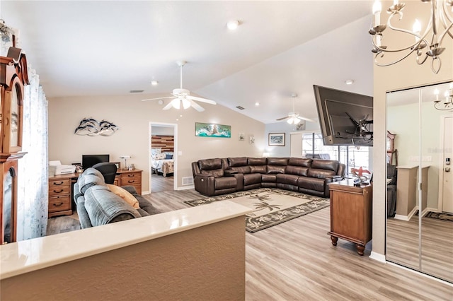 living room featuring vaulted ceiling, ceiling fan with notable chandelier, and light hardwood / wood-style floors