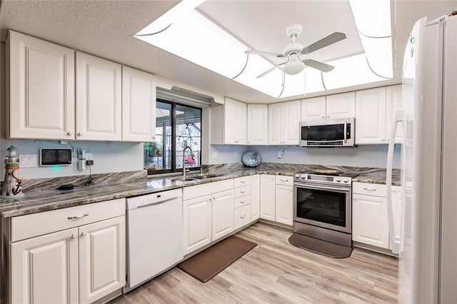 kitchen featuring appliances with stainless steel finishes, sink, white cabinetry, light hardwood / wood-style floors, and ceiling fan