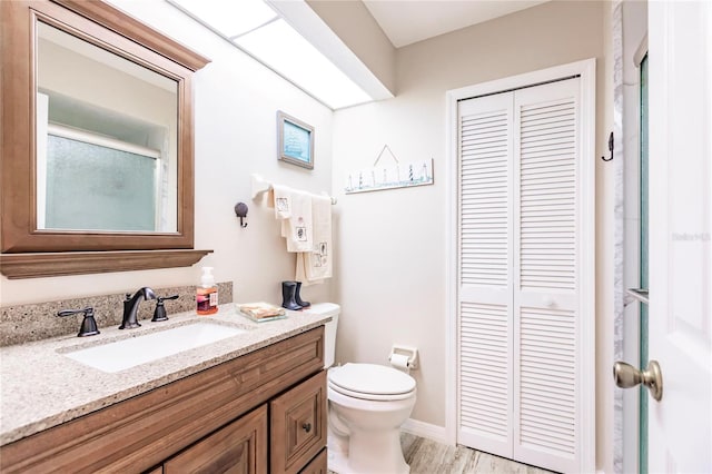 bathroom featuring vanity, hardwood / wood-style flooring, toilet, and walk in shower