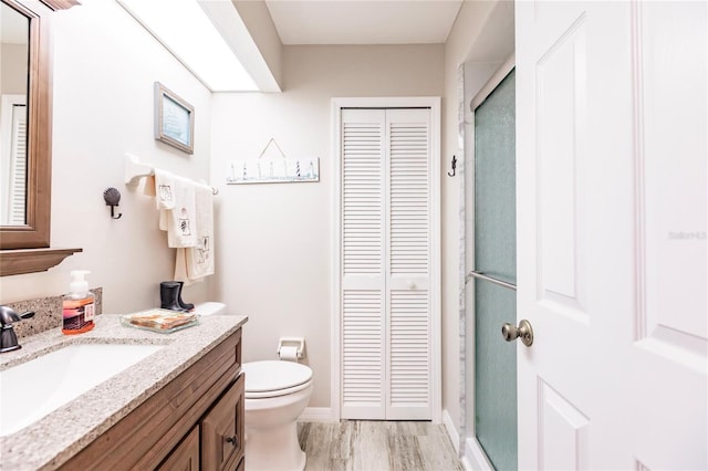 bathroom with vanity, toilet, hardwood / wood-style flooring, and an enclosed shower