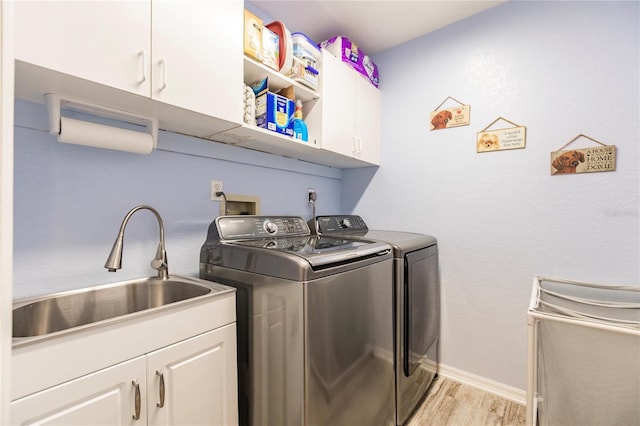 washroom featuring independent washer and dryer, cabinets, sink, and light hardwood / wood-style floors