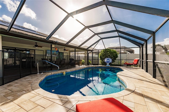 view of pool featuring a patio area, glass enclosure, and ceiling fan