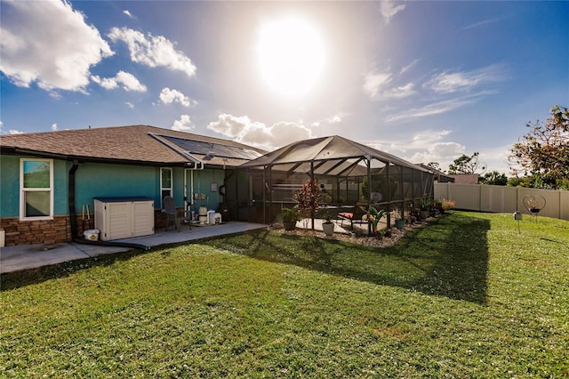 rear view of property with a patio, a lawn, and a lanai