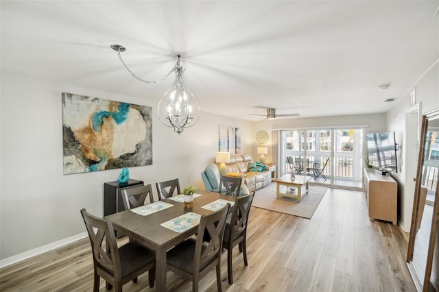 dining space with hardwood / wood-style flooring and ceiling fan with notable chandelier