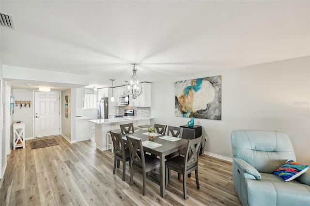 dining room featuring light hardwood / wood-style flooring and an inviting chandelier