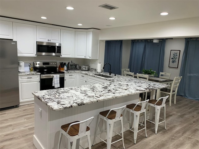 kitchen with a kitchen breakfast bar, white cabinetry, kitchen peninsula, and stainless steel appliances