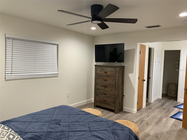 bedroom with a closet, ceiling fan, a spacious closet, and light wood-type flooring