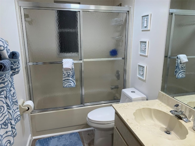 full bathroom featuring vanity, enclosed tub / shower combo, hardwood / wood-style flooring, and toilet